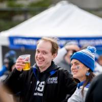 Two alumni smile and cheers at the tailgate